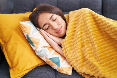Young beautiful hispanic woman lying on sofa sleeping at home