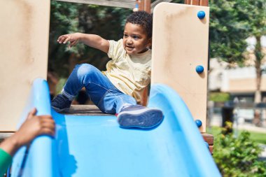 Baba ve oğul oyun alanında kaydırak oynuyorlar.