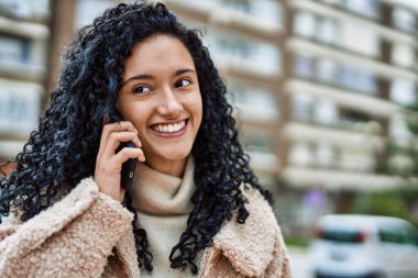 Genç İspanyol kadın gülümsüyor. Kendine güveniyor. Akıllı telefondan konuşuyor.
