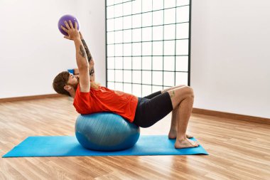 Genç kızıl adam spor merkezinde formda top kullanıyor.