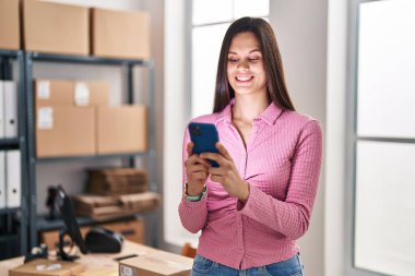 Genç, güzel, İspanyol bir kadın. İş kadını. Ofiste akıllı telefon kullanıyor.