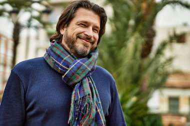 Parkta gülümseyen orta yaşlı yakışıklı adam.