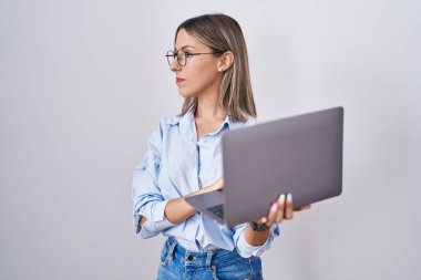 Young woman working using computer laptop looking to side, relax profile pose with natural face and confident smile. 