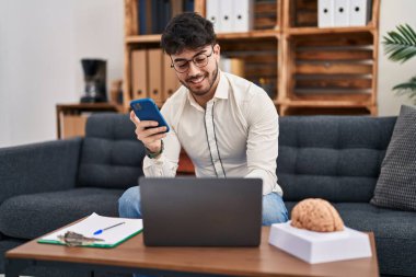 Laptop ve akıllı telefon psikoloji merkezi kullanan genç bir İspanyol psikolog.