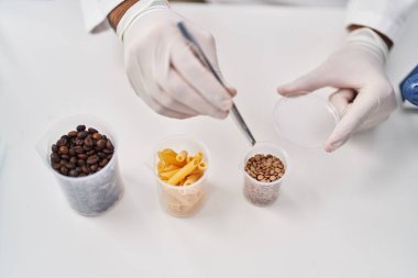 Genç İspanyol bilim adamı laboratuvarda cımbızla örnek tutuyor.