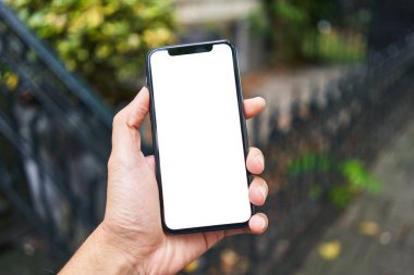 Elinde akıllı telefon tutan adam sokakta beyaz beyaz ekran gösteriyor