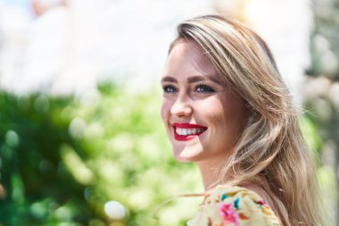 Genç, güzel, İspanyol bir kadın, gülümsüyor. Parkta kendine güveniyor.