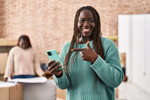 アフリカの女性使用スマートフォンで新しい家の笑顔幸せなポインティングで手と指 — ストック写真