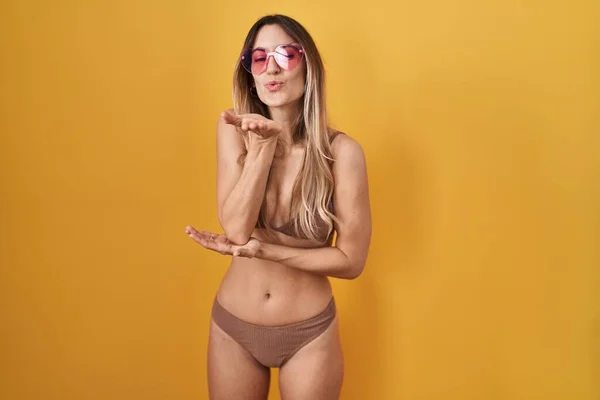Young Hispanic Woman Wearing Bikini Yellow Background Looking Camera Blowing — Φωτογραφία Αρχείου