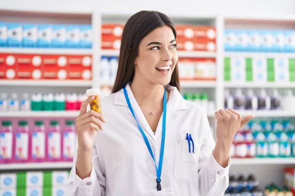 Mulher Hispânica Trabalhando Farmácia Farmácia Segurando Pílulas Apontando Polegar Para — Fotografia de Stock
