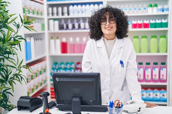 Young middle eastern woman pharmacist smiling confident standing at pharmacy