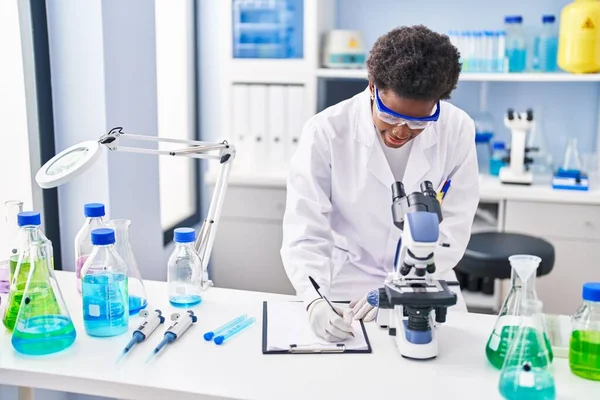 African American Woman Wearing Scientist Uniform Using Microscope Write Clipboard — ストック写真
