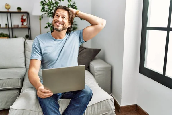Hombre Guapo Mediana Edad Usando Computadora Portátil Sofá Sonriendo Seguro —  Fotos de Stock