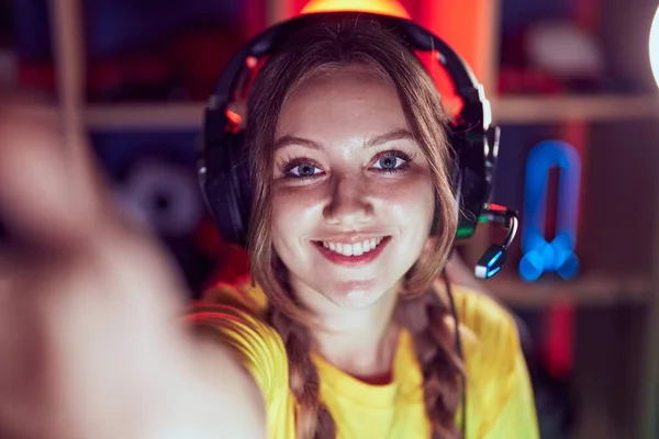 年轻的金发女子面带微笑自信地在游戏室用相机自拍 — 图库照片