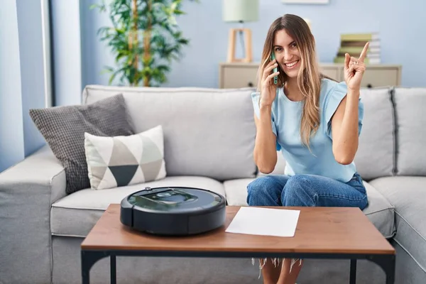 Young Hispanic Woman Sitting Home Vacuum Robot Speaking Phone Smiling — Stockfoto