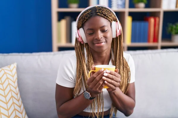 African american woman listening to music drinking coffee at home