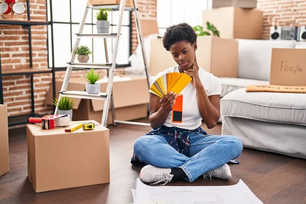African American Woman Choosing Paint Color Sitting Floor New Home — стоковое фото