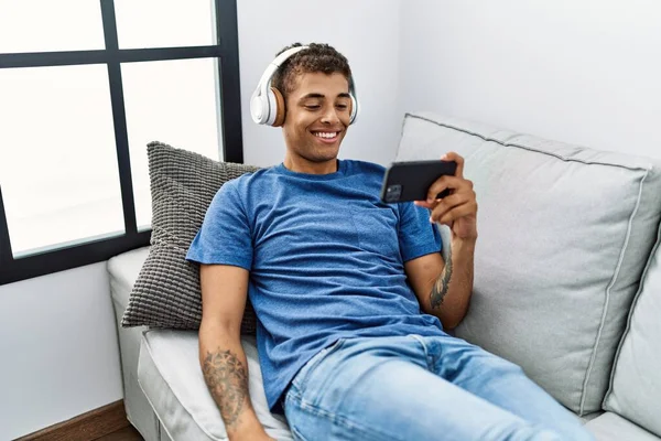 Young Hispanic Man Sitting Sofa Watching Video Smartphone Home — ストック写真