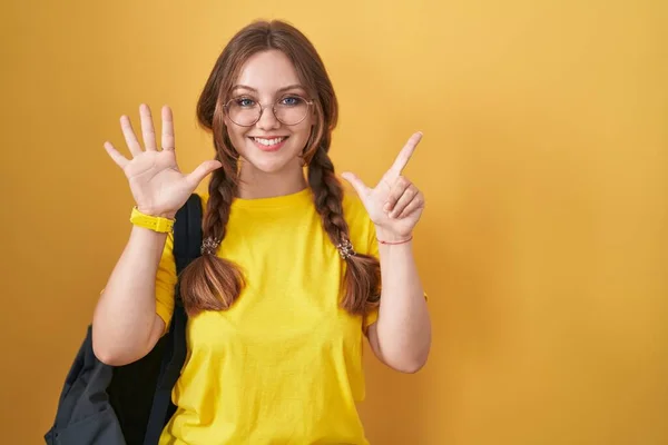 Młoda Kaukaska Kobieta Studenckim Plecaku Żółtym Tle Pokazuje Wskazuje Palcami — Zdjęcie stockowe