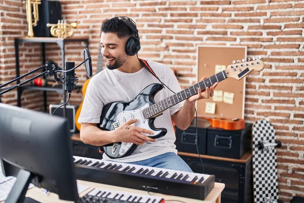Genç Arap sanatçı müzik stüdyosunda elektro gitar çalarak şarkı söylüyor.