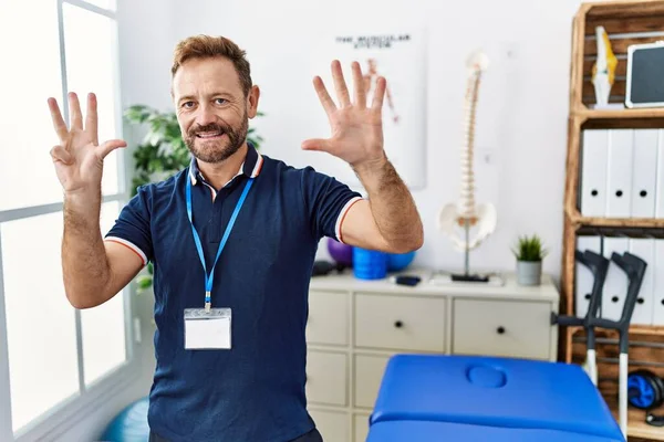 Orta Yaşlı Fizyoterapist Ağrı Kesici Kliniğinde Çalışıyor Numarayı Gösterip Işaret — Stok fotoğraf