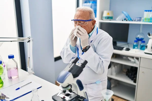研究室でナプキンを使用して科学者の制服を着てシニア男 — ストック写真