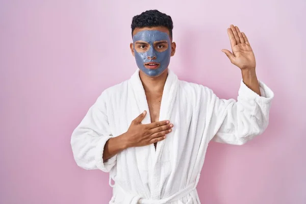 Young Hispanic Man Wearing Beauty Face Mask Bath Robe Swearing — Stockfoto