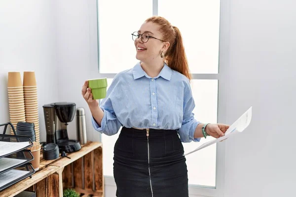 若いです赤毛女性笑顔自信を持って飲むコーヒーにオフィス — ストック写真