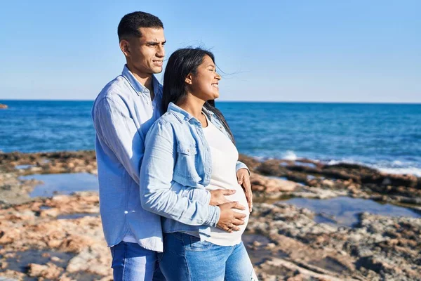 Young Latin Couple Expecting Baby Hugging Each Other Standing Seaside — Stock fotografie
