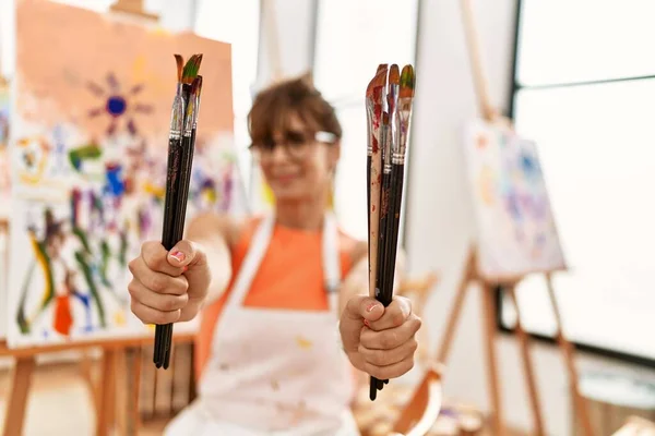 年轻的惊慌失措的女人微笑着 自信地拿着画笔在艺术工作室里 — 图库照片