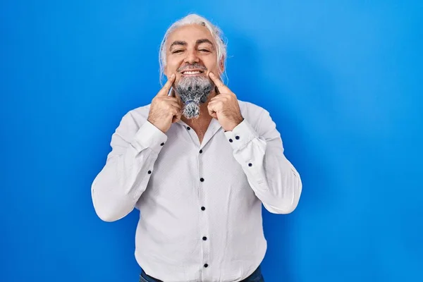 Мужчина Средних Лет Седыми Волосами Стоящими Синем Фоне Улыбаясь Открытым — стоковое фото