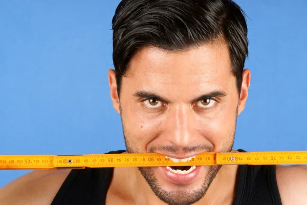 Carpenter worker biting a wooden metric ruler — Stock Photo, Image