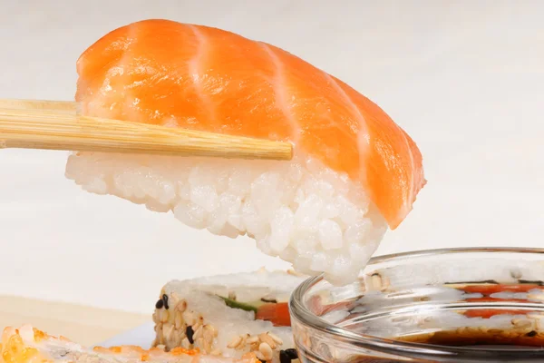 Pałeczki trzymając kawałek sushi nigiri — Zdjęcie stockowe