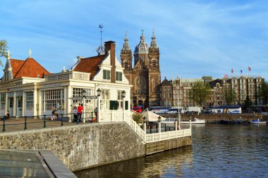 Amsterdam, Hollanda - 7 Ağustos 2017: Tren İstasyonu Meydanı 'ndaki Turizm Bilgi Merkezi ve Amsterdam, Hollanda' daki arka plandaki Aziz Nicholas Bazilikası. Etrafta birileri var..