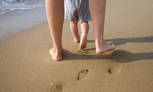 Mãe e criança caminhando em uma praia de areia — Fotografia de Stock
