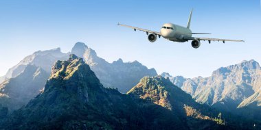 Uçak yazın gün batımında sisin içinde dağların üzerinden uçuyor. Yolcu uçağıyla manzara, alçak bulutlarda tepeler, mavi gökyüzü. Beyaz uçak. İş seyahati.