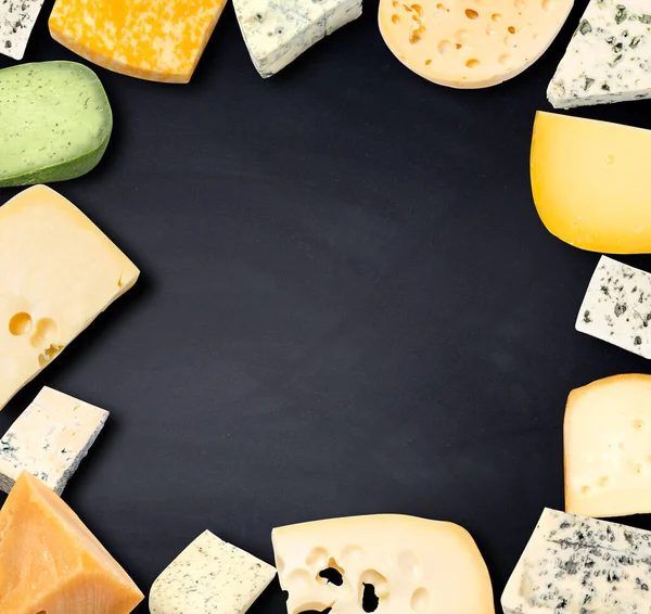 Various types of cheese on a black wooden table. View from above. Space for copying.
