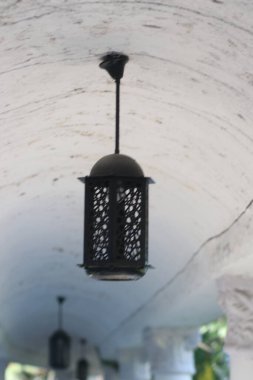 Beyaz tavanda siyah desenli bir fener asılı.