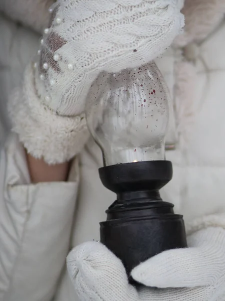 Mãos em mitenes segurar uma lâmpada antiga iluminada — Fotografia de Stock