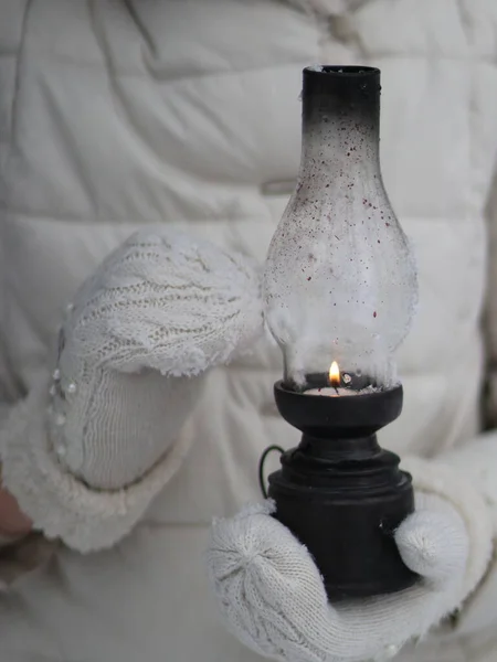 Hände in Fäustlingen halten eine entzündete antike Lampe — Stockfoto