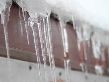 Karlı bir çatıda sallanan buz saçakları.