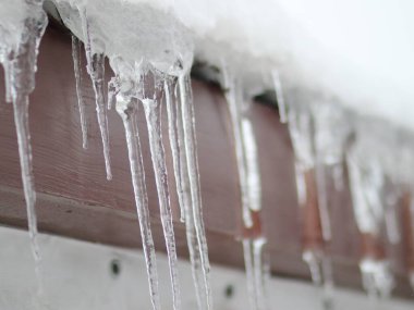 Karlı bir çatıda sallanan buz saçakları.