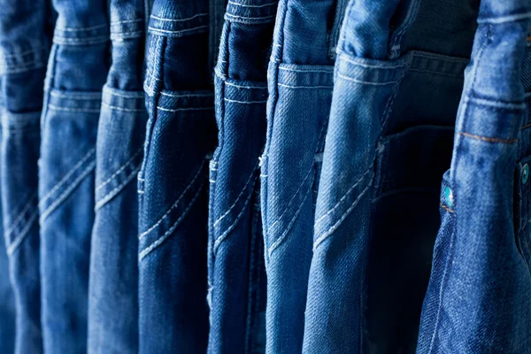 Row of hanged blue jeans in a shop — Stock Photo, Image