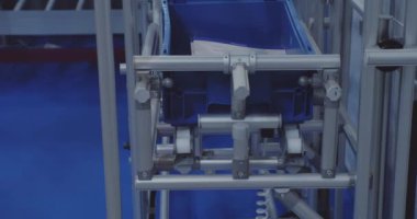 Bir plastik kutu, deponun içindeki bir taşıyıcı boyunca hareket ediyor. Modern depo ekipmanları. yakın plan