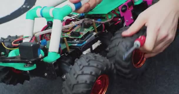 Ремонт маленького робота на колесах с отверткой. руки рабочего крупным планом — стоковое видео