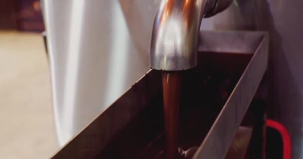 Nowoczesny sprzęt do przemysłowej produkcji żywności.a strumień gorącej roztopionej czekolady wylewa się z rurociąg.proces technologiczny zbliżenie — Wideo stockowe
