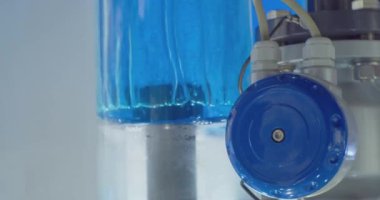 Modern teknoloji. Pompa donanımı. Güzelce aydınlatılmış sıvı şeffaf bir cam tüpe pompalanır. Yakın plan.