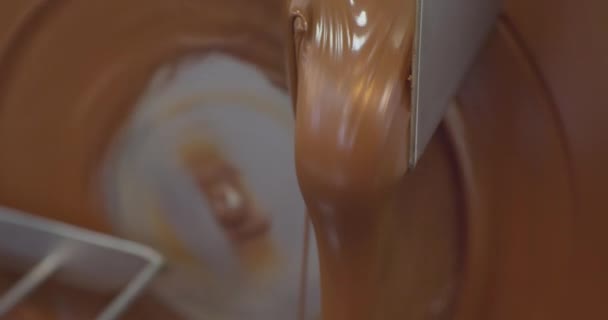 Βιομηχανική παραγωγή τροφίμων. Περιστρεφόμενος δίσκος σοκολατομηχανής με ζεστή λιωμένη καφέ σοκολάτα. τεχνολογική διαδικασία close-up — Αρχείο Βίντεο