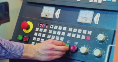 Tanımlanamayan kişi fabrikadaki üretim makinesinin kontrol panelinin arkasında çalışıyor. Yakın plan.