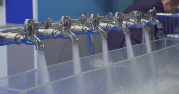 Chorros de agua limpia se vierten de varios grifos mezcladores de metal.. Primer plano — Vídeos de Stock